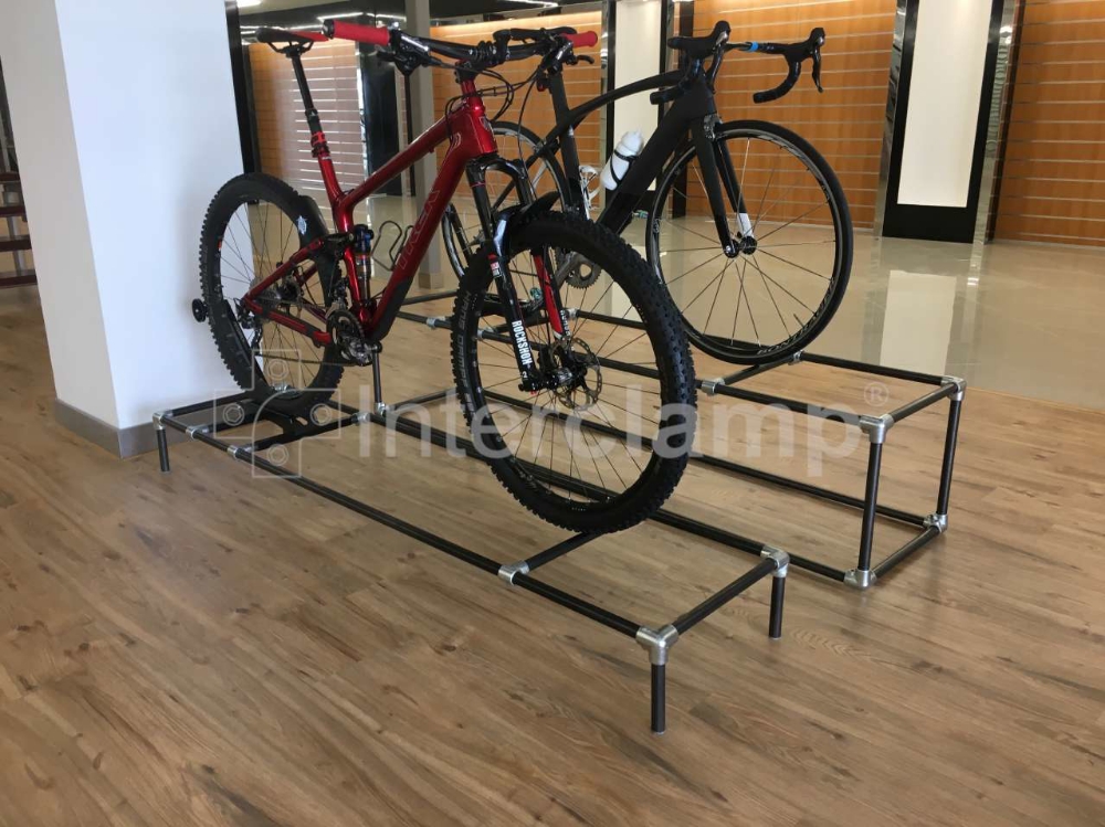 Close-up of a custom bike display stand made from black powder-coated Interclamp key clamp fittings, showcasing its sturdy and stylish design